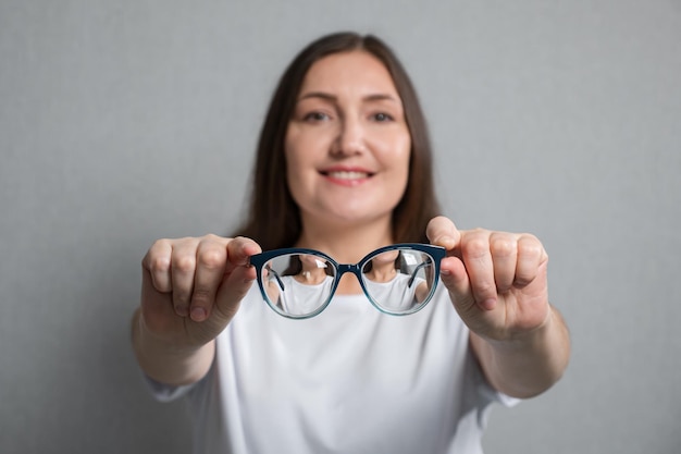 Primer plano de gafas con lentes de aumento sobre fondo borroso de mujer joven