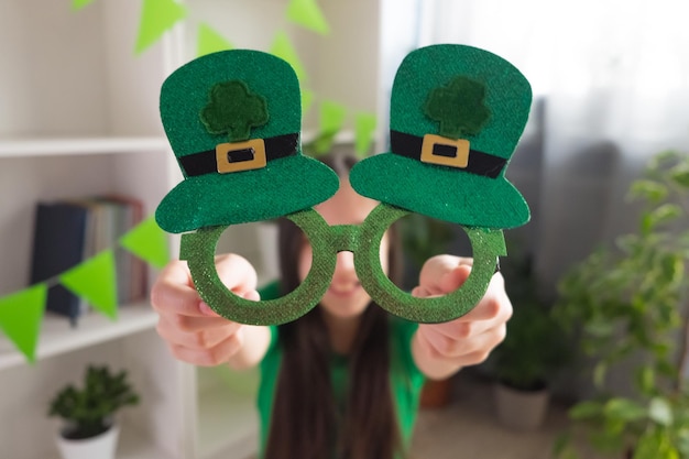 Primer plano de gafas que una niña sostiene en sus manos para el Día de San Patricio