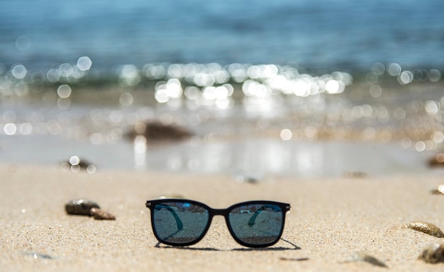 Primer plano de gafas de sol en la arena en la playa contra el cielo