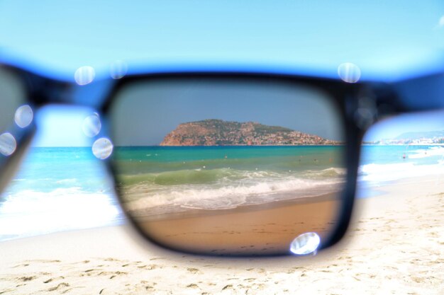 Foto primer plano de gafas de sol en la playa contra el cielo