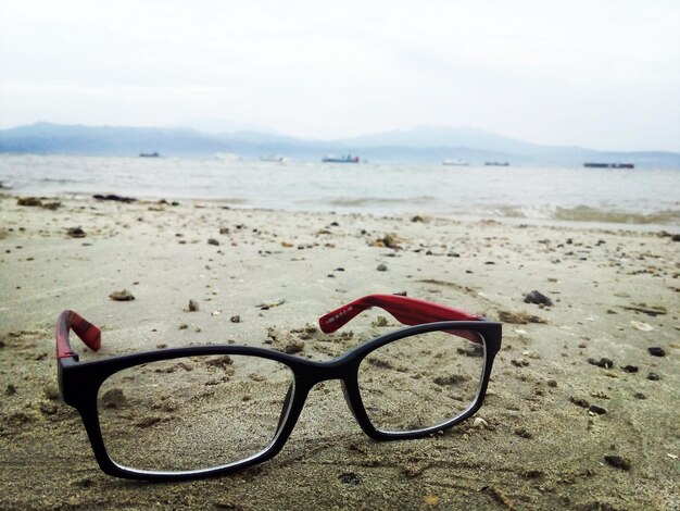 Foto primer plano de gafas de sol en la playa contra el cielo