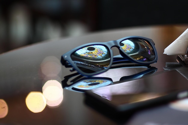 Primer plano de gafas de sol con el reflejo del globo por teléfono inteligente en la mesa