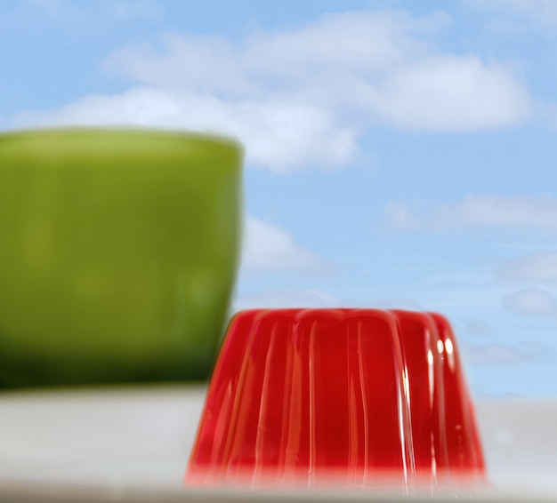 Primer plano de una gelatina de fresa con un vaso verde y un cielo nublado en el fondo