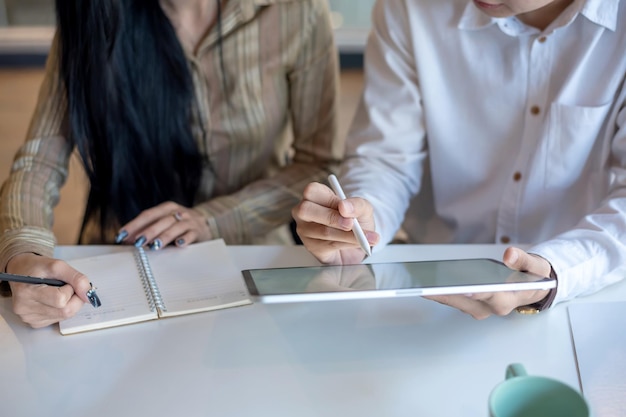 Primer plano de gente de negocios haciendo lluvia de ideas trabajando juntos tomando notas y usando tableta en la oficina