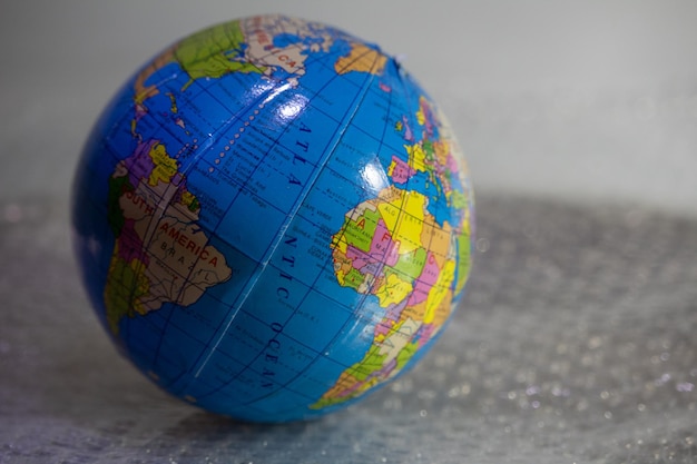 Foto primer plano de un globo que representa la tierra sobre una mesa cubierta de papel de burbujas con textura