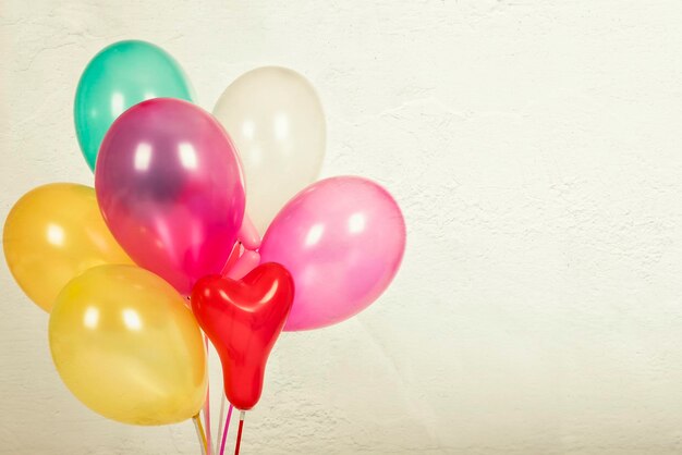 Primer plano de globos de helio multicolores contra la pared