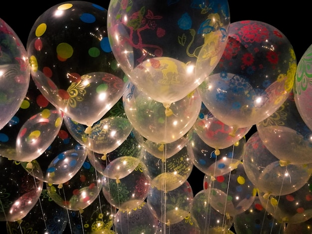 Primer plano de globos multicolores que vuelan contra un fondo negro