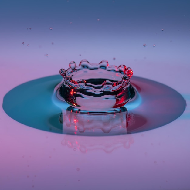 Primer plano de una gota cayendo sobre el agua contra un fondo azul