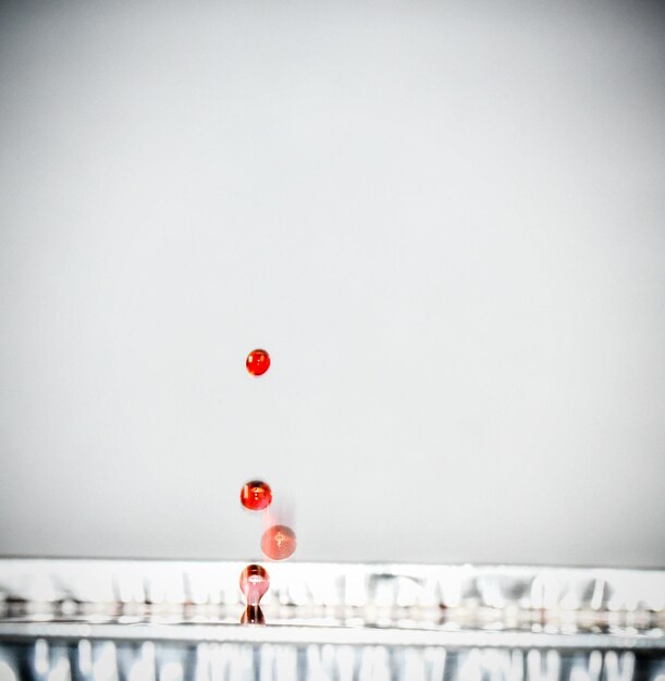 Foto primer plano de gotas rojas que caen en el agua contra un fondo gris