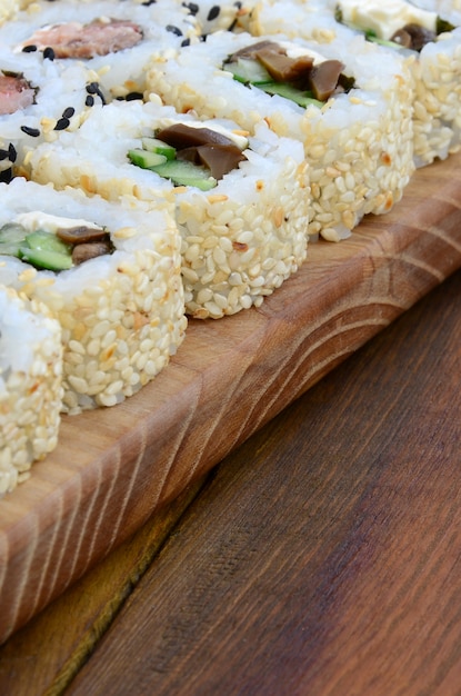 Primer plano de una gran cantidad de rollos de sushi con diferentes rellenos se encuentran en una superficie de madera