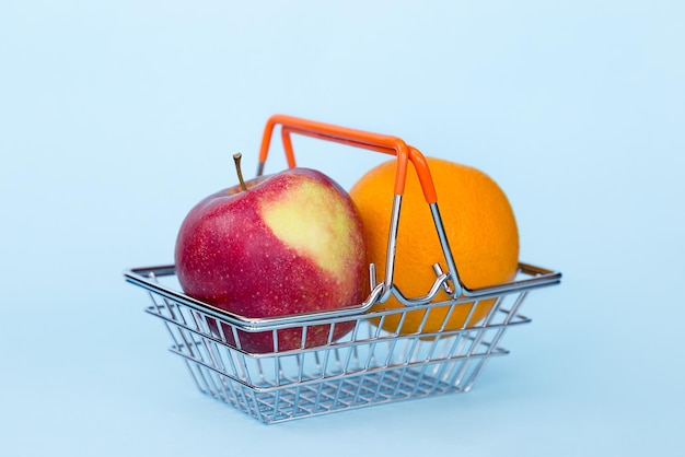Primer plano de una gran manzana roja y naranja en el carrito sobre un fondo azul