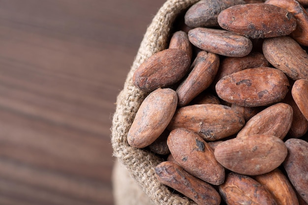 Primer plano de granos de cacao fritos en una bolsa contra una mesa de madera oscura