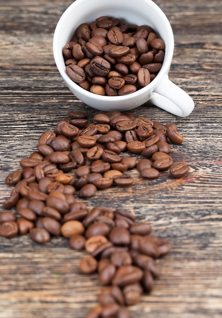 Primer plano de los granos de café en una forma completa para una bebida, granos de café aromáticos en una taza, granos de café para hacer un delicioso café en una taza