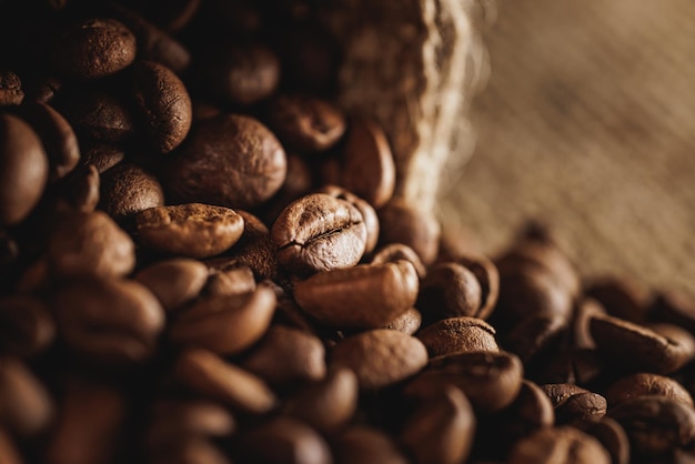 Primer plano de granos de café recién tostados esparcidos de una bolsa de arpillera.