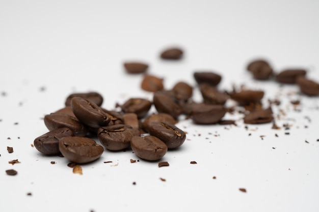 Primer plano de granos de café tostado con fondo blanco.