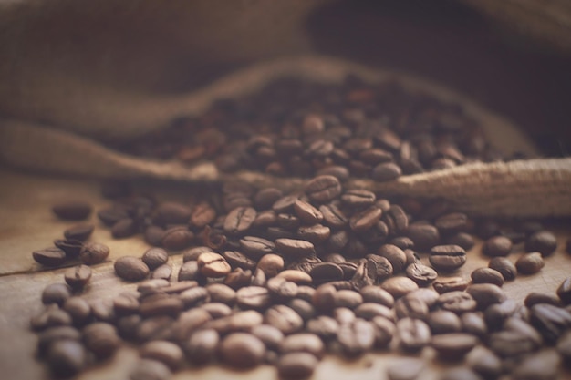 Primer plano de granos de café tostados esparcidos sobre la mesa