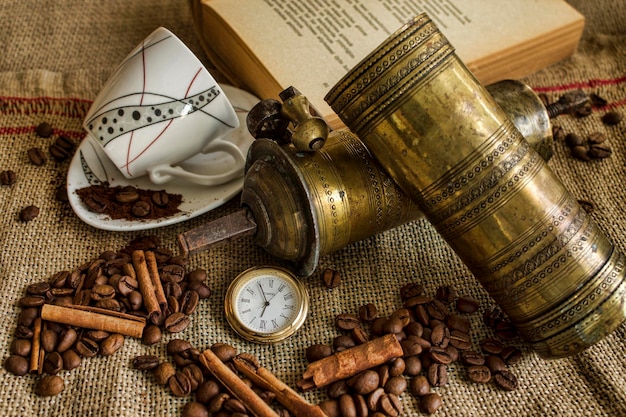 Primer plano de granos de café tostados con libro y reloj de bolsillo en el saco