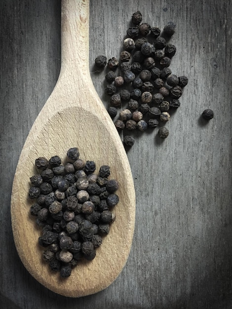 Foto primer plano de granos de pimienta negra en una cuchara de madera