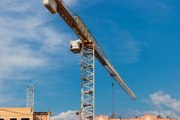 Primer plano de la grúa torre sobre un fondo de cielo azul. Construcción de viviendas modernas. Ingeniería Industrial. Construcción de vivienda hipotecaria.