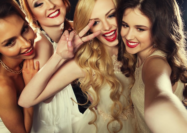 Primer plano de un grupo de chicas riéndose que tienen una fiesta toman selfie con un teléfono inteligente