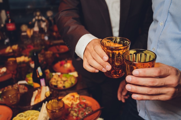 Primer plano de un grupo de personas tintineando copas con vino o champán frente a bokeh