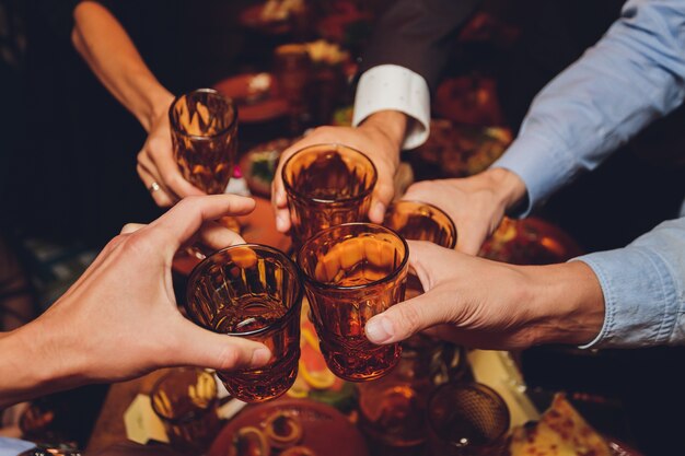 Primer plano de un grupo de personas tintineando copas con vino o champán frente a bokeh