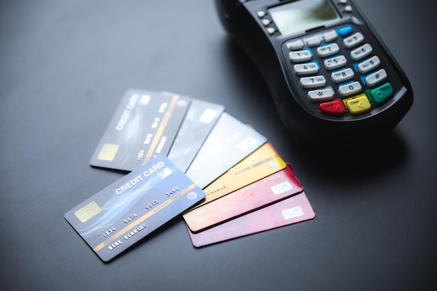 Primer plano de un grupo de tarjetas bancarias de crédito y débito con máquina NFC en una mesa azul utilizada para transferencias de dinero en línea y de plástico mientras compra o paga facturas
