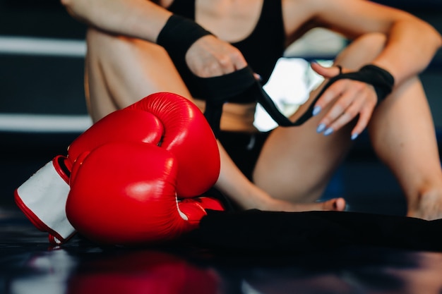 Primer plano de guantes de boxeo rojos en el suelo de un ring de boxeo azul.