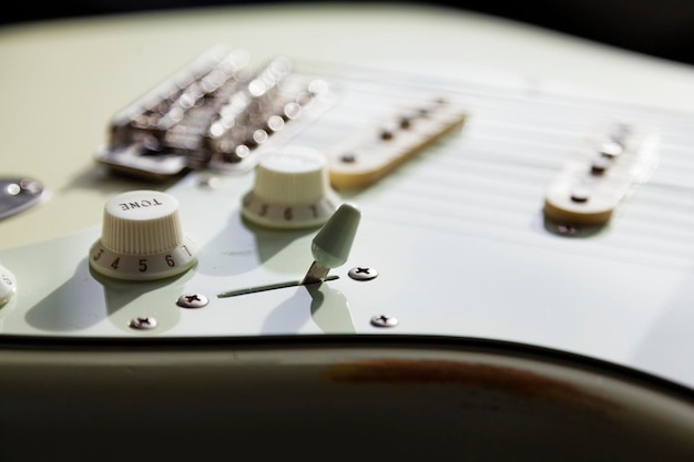 Foto primer plano de una guitarra eléctrica blanca con cuerdas y botones