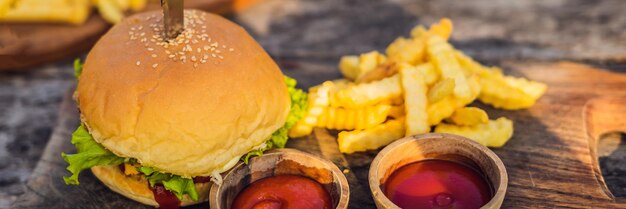 Primer plano de hamburguesa fresca con papas fritas en la mesa de madera con tazones de comida de estilo de vida de salsa de tomate