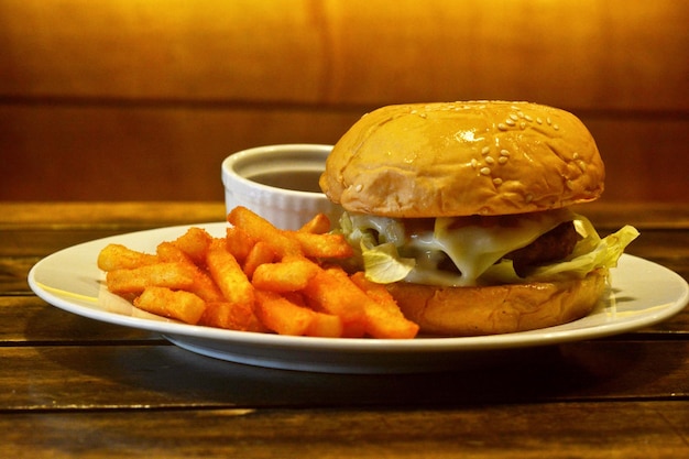 Foto primer plano de una hamburguesa y papas fritas servidas en un plato en la mesa