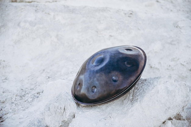 Primer plano de handpan o colgar con desierto en el fondo El Hang es un instrumento musical de tambor étnico tradicional