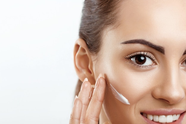 Primer plano de una hermosa chica con productos de belleza en la piel suave maquillaje natural tocando la cara