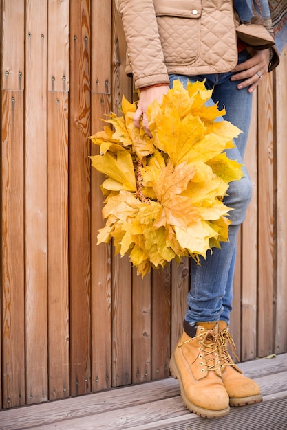 Primer plano de una hermosa corona de arce amarillo en manos de una mujer Chica sosteniendo hojas de otoño