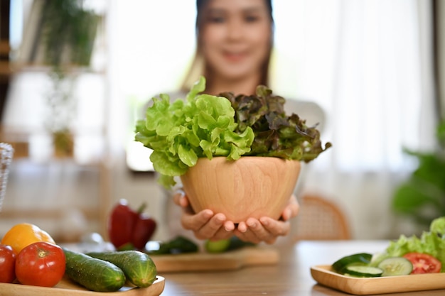 Primer plano Hermosa mujer asiática sosteniendo una ensaladera fresca sobre la mesa del comedor