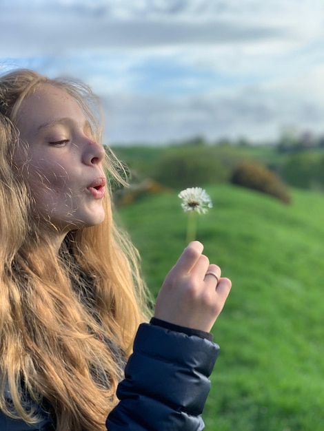 Foto primer plano de una hermosa mujer joven con pétalos de flores en el campo contra el cielo