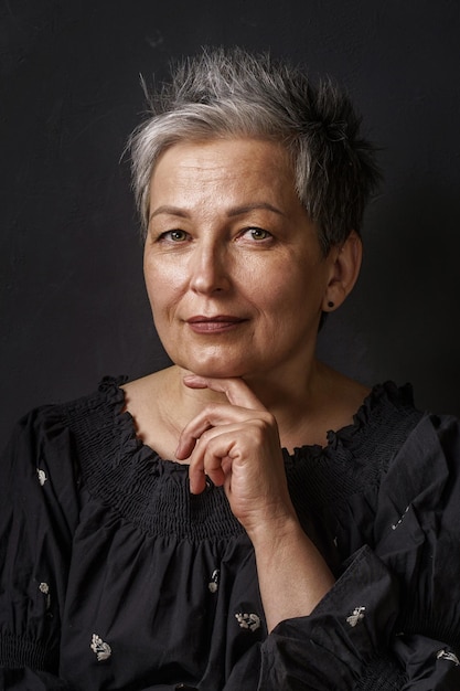 Foto primer plano hermosa mujer de negocios madura con cabello gris posando barbilla inclinada en su mano aislada sobre fondo negro mujer elegante gris con cabello corto imagen de mujer madura exitosa belleza envejecida