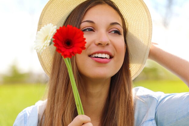 Foto primer plano de una hermosa mujer con sombrero sosteniendo flores