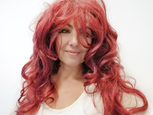 Foto primer plano de una hermosa mujer sonriente con cabello rojo contra un fondo blanco