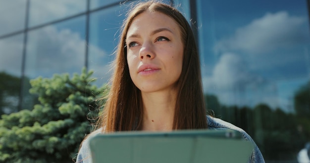 Primer plano hermosa mujer trabajando en una computadora de tableta al aire libre Chica leyendo noticias en una tableta en la calle de la ciudad Concepto de tecnología