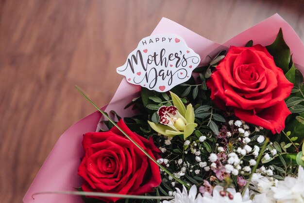 Primer plano de un hermoso ramo de rosas con una tarjeta del día de la madre feliz Concepto del Día de la Madre de felicitaciones por la tarjeta de regalo de vacaciones