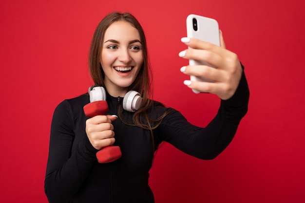 primer plano, hermoso, sonriente, positivo, pared joven, mujer, llevando, negro, deporte, ropa, blanco