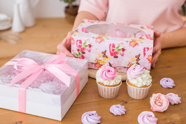 Primer plano de hermosos cupcakes en una caja de regalo. Magdalenas caseras con crema y merengue en envases festivos