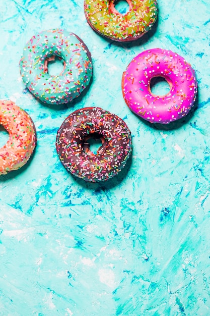 Primer plano de hermosos donuts dulces multicolores en un plato sobre fondo azul grunge con espacio de copia. Comida, restaurante, concepto de panadería.