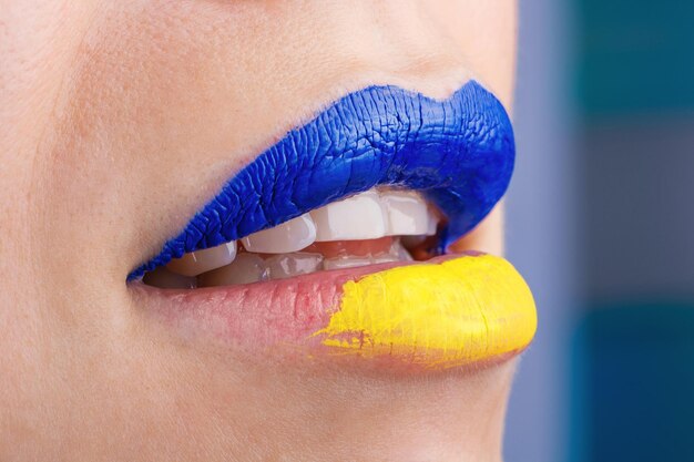 Foto primer plano de hermosos y gordos labios femeninos pintados en azul y amarillo labios de mujer pintados en