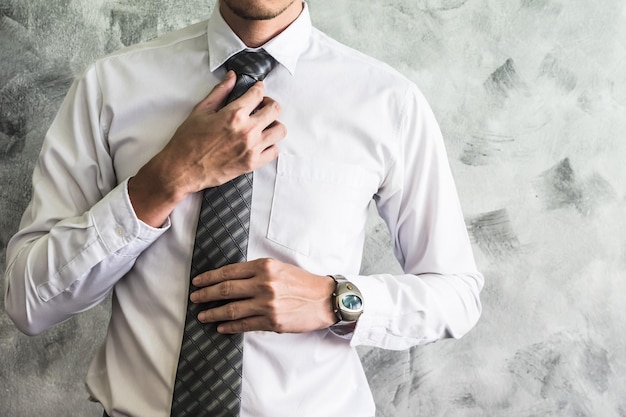 Primer plano del hombre ajustando su corbata en el fondo del grunge