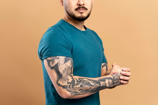 Primer plano de un hombre asiático serio con el brazo tatuado con estilo aislado sobre fondo beige