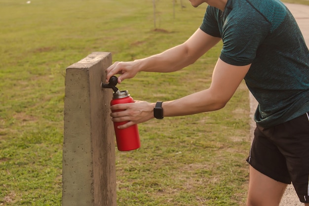 Primer plano de un hombre atlético que lleva agua de la fuente pública.