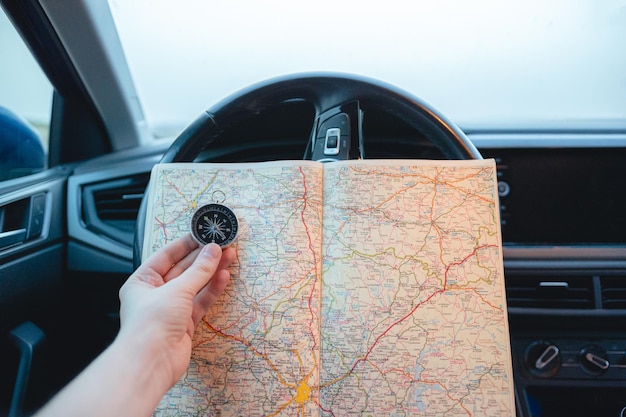 Primer plano de un hombre con una brújula y un mapa en sus manos dentro de un coche