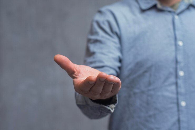 Foto un primer plano de un hombre con una camisa muestra el gesto de la mano rocknroll contra una pared de hormigón